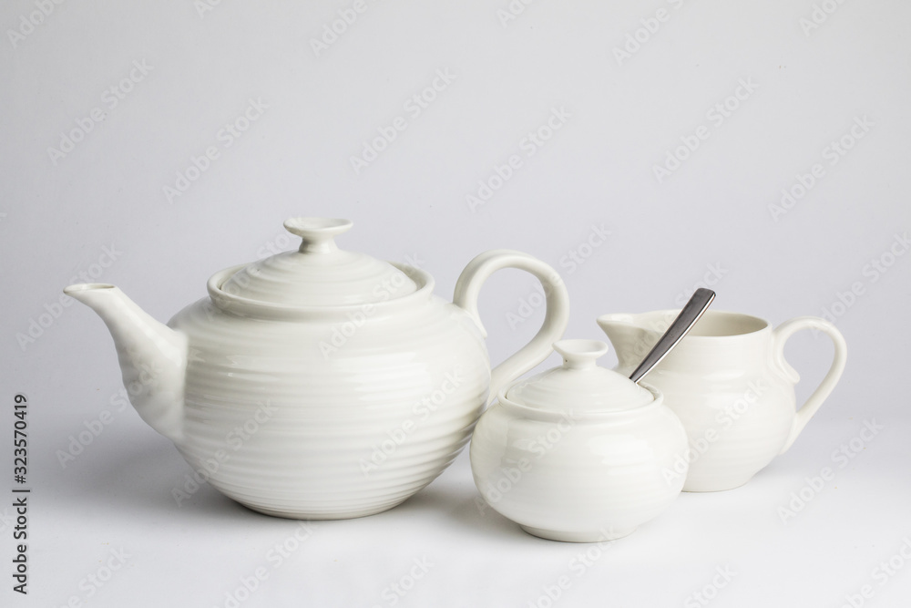 a white ceramic teapot sugar and cream set on a wooden table top a white ceramic teapot sugar and cream set on a wooden table top