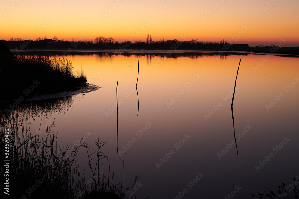 Caorle, Venice, Italy, 01012020: Sunset on Caorle lagoon with amazing orange sky colours and dark blue sea. Caorle, Venice, Italy, 01012020: Sunset on Caorle lagoon with amazing orange sky colours and dark blue sea.