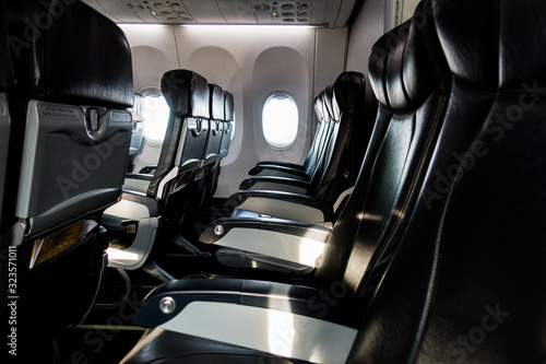 Empty passenger seats in airplane with light shining through the window.
