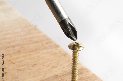 a macro selective focus lose up of a phillips cross style screwdriver and phillips cross style wood screw isolated on white