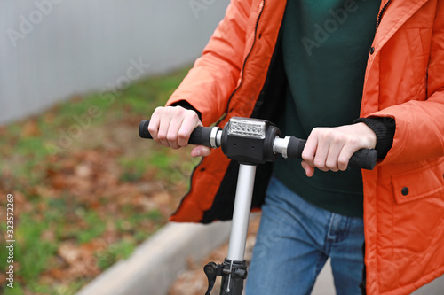 Teenage boy riding kick scooter outdoors, closeup