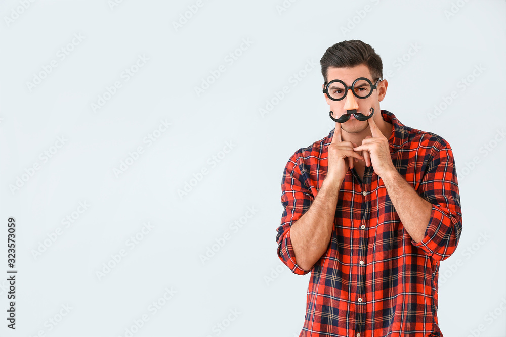 Man in funny disguise on light background. April fools' day celebration Man in funny disguise on light background. April fools' day celebration