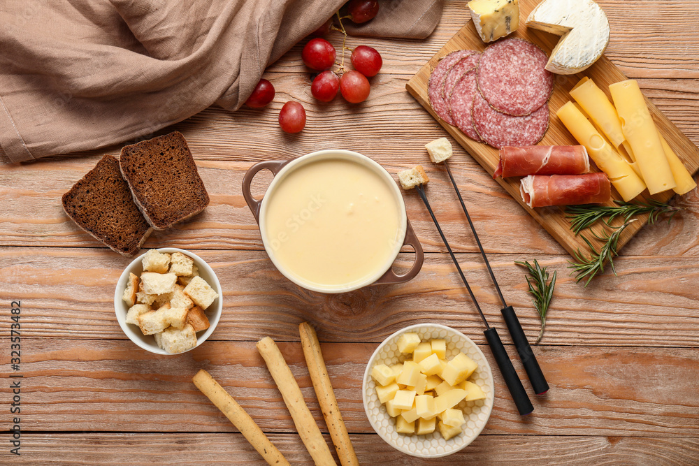 Fototapeta premium Cheese fondue with snacks on wooden background