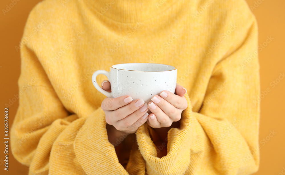 Beautiful young woman in warm sweater and with hot tea on color background, closeup Beautiful young woman in warm sweater and with hot tea on color background, closeup