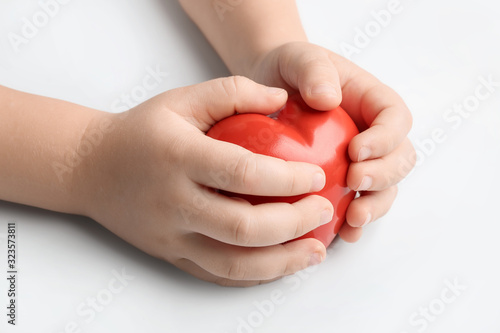 Child s hands with red heart on white background. Cardiology concept