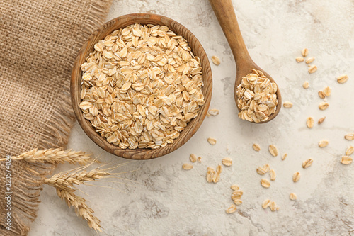 Bowl and spoon with raw oatmeal on table photo