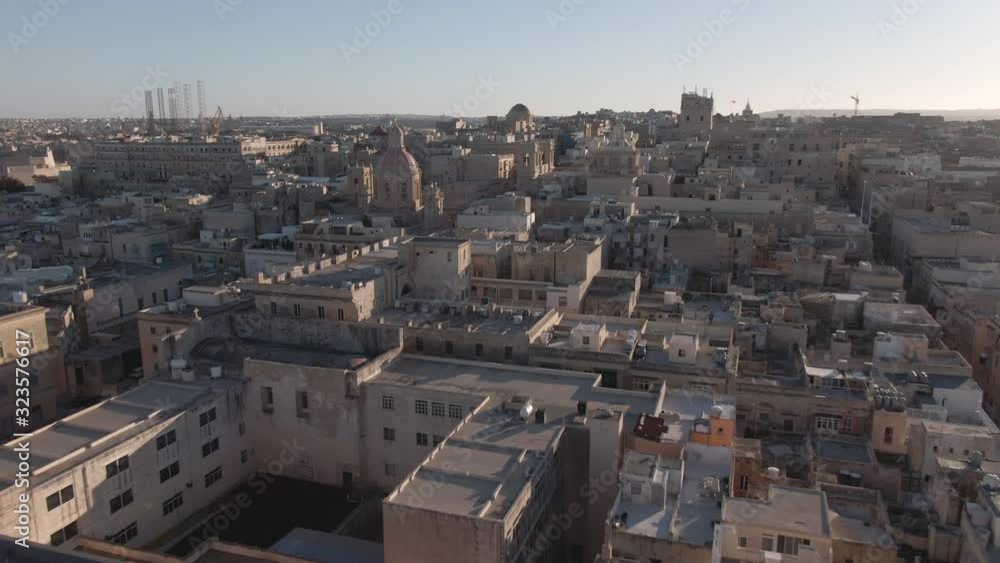 Flies low over the roofs of European houses in the capital of Malta, Valletta, the Mediterranean Sea at sunset in the background. Drone video Flies low over the roofs of European houses in the capital of Malta, Valletta, the Mediterranean Sea at sunset in the background. Drone video