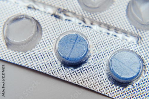 blue pills in silver packaging on a light background