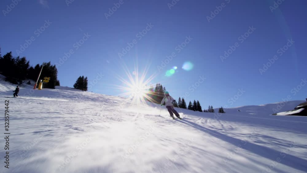 girl skier skiing on slopes in the Swiss alps, sun rays and flare in the background girl skier skiing on slopes in the Swiss alps, sun rays and flare in the background