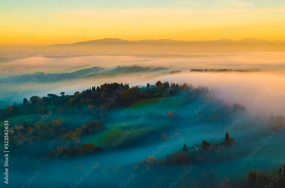 Tuscany hilly, foggy, sunset scenery; as seen from one of the towers in San Gimignano, Italy.