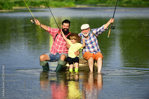 Happy Grandfather with son and grandson having fun in river. Men day. Father, son and grandfather on fishing trip.