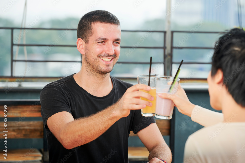 Happy smiling young people clinking glasses with sweet delicious cocktails when celebrating success in cafe Happy smiling young people clinking glasses with sweet delicious cocktails when celebrating success in cafe