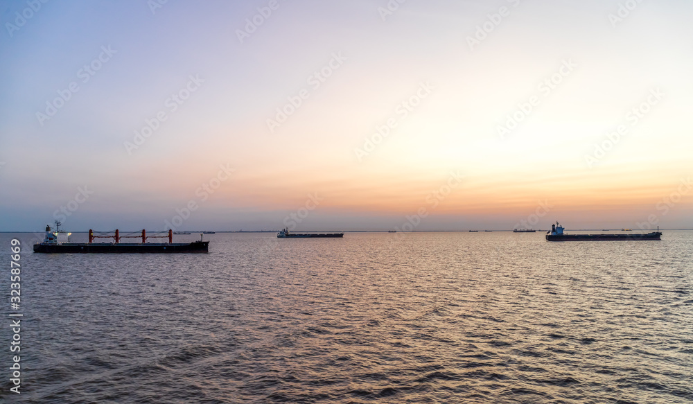 Cargo ships at sunset anchored off Buenos Aries waiting to load freight.