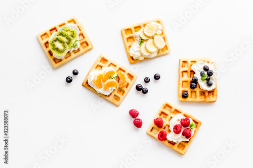 Beautiful yummy snacks. Waffles with cream and friuits on white background top-down