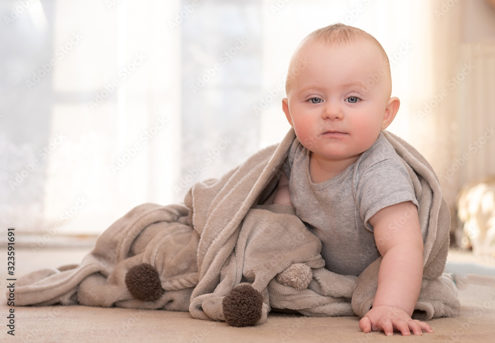 Naklejka premium Caucasian infant sitting on floor leaning on one hand
