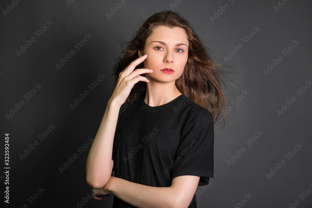 Portrait of a beautiful, young girl in black clothes with long hair. Studio photo, on a gray background. A model with clean skin. Portrait of a beautiful, young girl in black clothes with long hair. Studio photo, on a gray background. A model with clean skin.