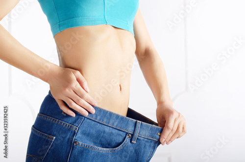 Caucasian female model in blue jeans showing her flat stomach. Weightloss concept.