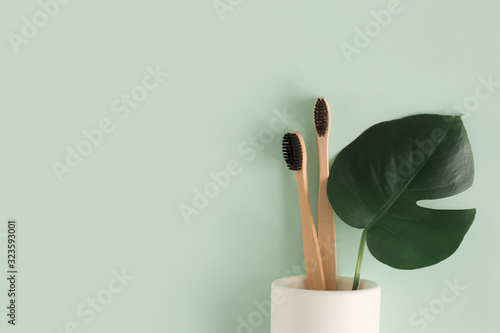 Zero waste concept. Top view Natural eco bamboo toothbrush in stand with monstera leaves on green background  top view Copy space