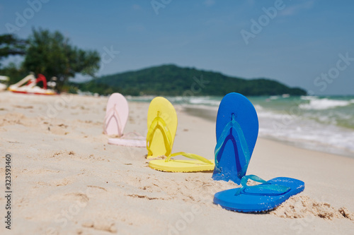 Colorful flip-flops on sandy beach, summer vacation and traveling concept