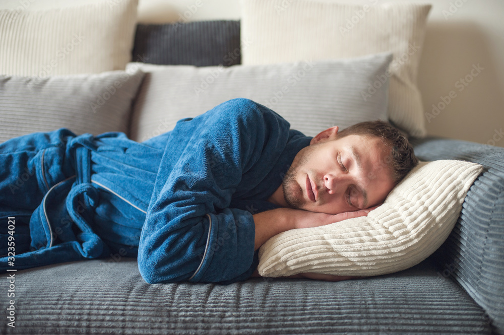 a man in a bathrobe lies on the couch and sleeps during the day a man in a bathrobe lies on the couch and sleeps during the day