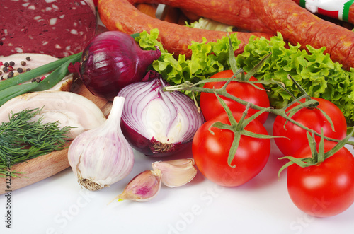 Meat products surrounded by vegetables on the kitchen board
