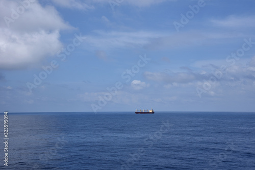 Landscape of the calm ocean with sailing cargo ship.  © Mariusz