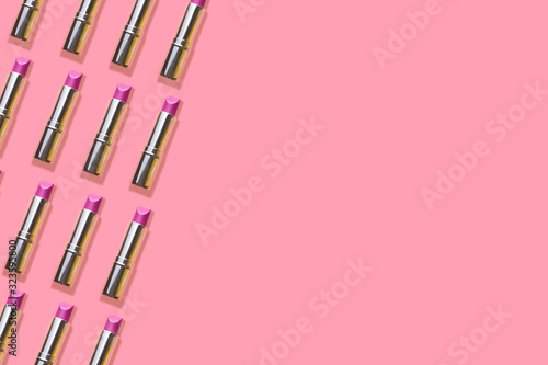 Pattern of magenta lipsticks on a pink background with copy space
