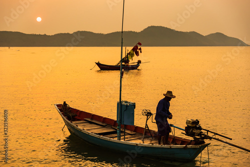 Chanthaburi, Thailand - February, 02, 2020 :Beautiful sunrise over sea with Silhouette of fishermen with yellow and orange sun in the background.