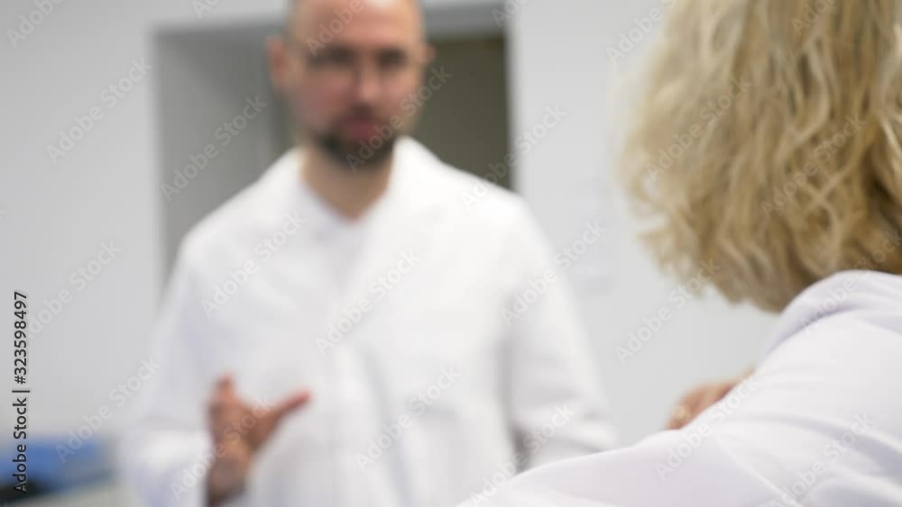 blurry view of 2 doctors discus the patients situation blurry view of 2 doctors discus the patients situation