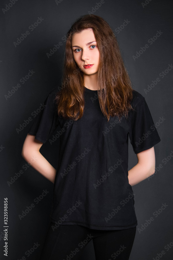 Beautiful, young girl with long hair, in black clothes, posing in studio on a gray background. A model with clean skin. Beautiful, young girl with long hair, in black clothes, posing in studio on a gray background. A model with clean skin.