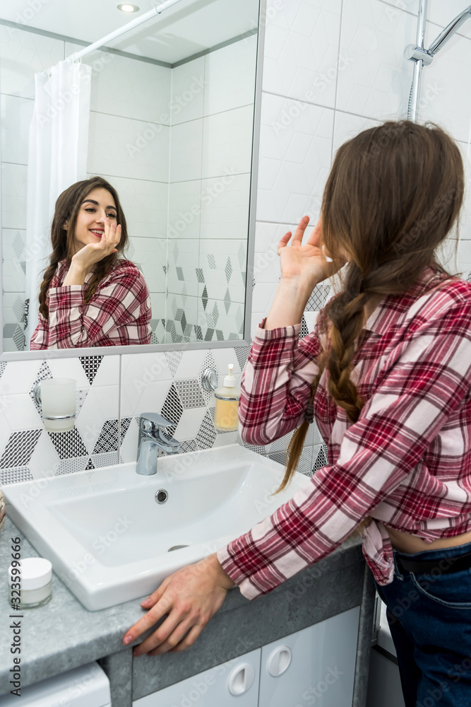 beautiful girl in the bathroom applies cream on her face. beauty concept beautiful girl in the bathroom applies cream on her face. beauty concept