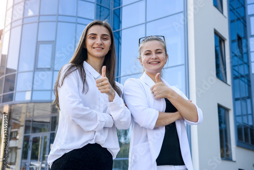 Happy women in business suits with folder standing before big business office Free Download Happy women in business suits with folder standing before big business office - GFXLoad