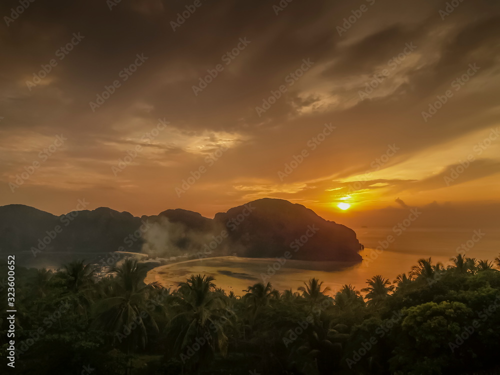 Top view evening of rock mountain, long beach and Loh Samah Bay with clouds moving and yellow light in cloudy sky background, sunset at panoramic view point, Phi Phi Don island, Krabi, Thailand.