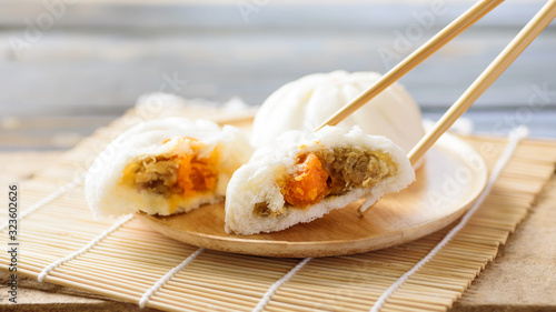 Steamed buns filled with minced pork and salted egg and chopsticks on wooden plate, Chinese food
