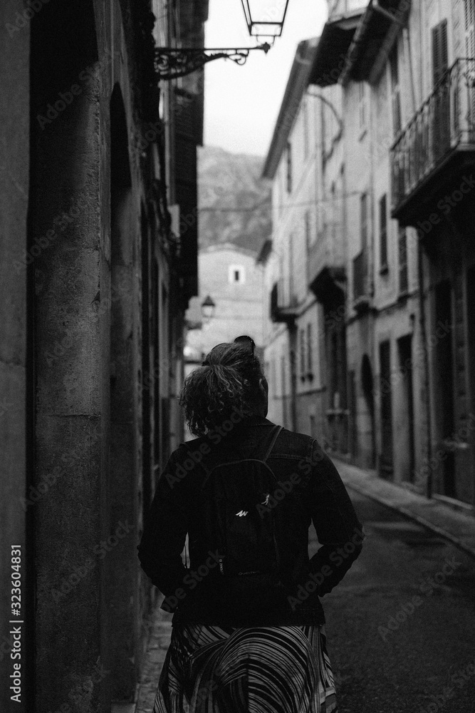 Girl walking down Spanish street, black and white 