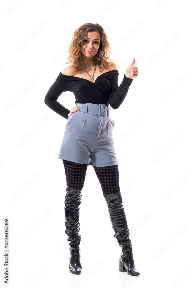 Expressive charming cutie young woman with curly hair in trendy clothes showing thumb up gesture. Full body isolated on white background. Expressive charming cutie young woman with curly hair in trendy clothes showing thumb up gesture. Full body isolated on white background.