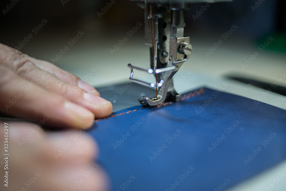 A man sews from leather on a sewing machine. Hands and sewing. Production of leather goods using a sewing machine
