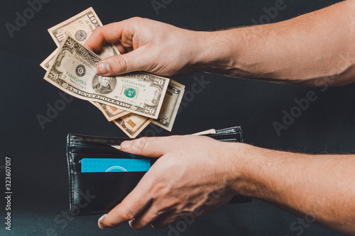 Leather wallet with money in male hands on dark background © Niko_Dali