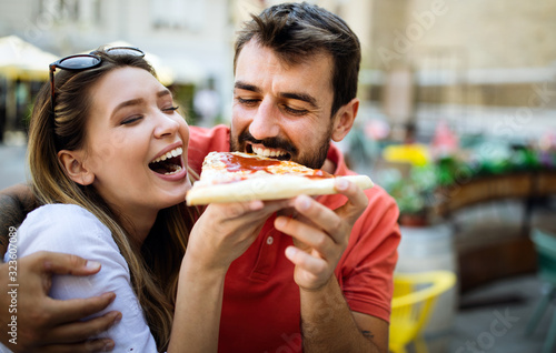 Happy couple eating pizza while traveling on vacation