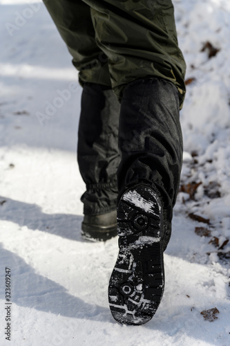 Man standing in the snow with protective covers and shows the sole.