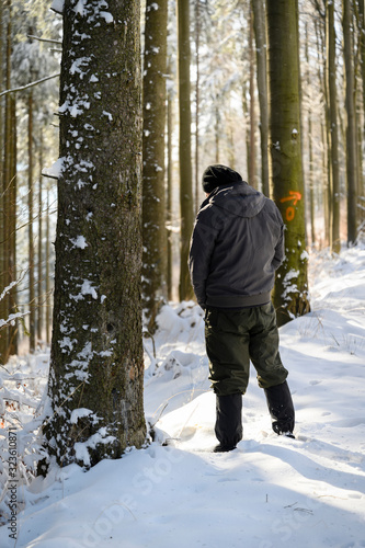 Fototapeta Man urinating in winter in snow on mountains in nature near forest