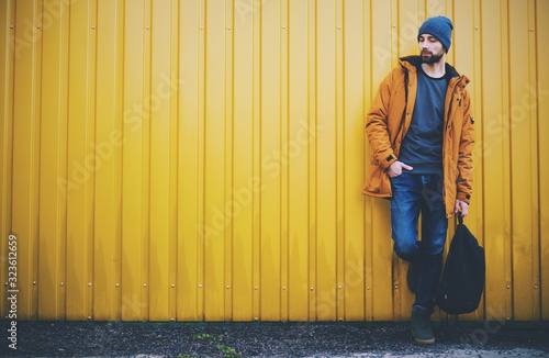 Young stiylish man near yellow background on the street. Hipster. Casual modern  style. © Yulia