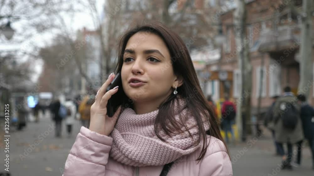 Stylish brunette girl chatting on her phone outdoors in autumn in slow motion Stylish brunette girl chatting on her phone outdoors in autumn in slow motion