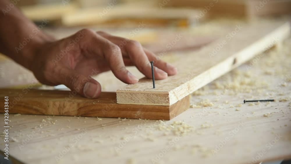 Young Asian group man worker using hammer to nail wood plank for build diy wood furniture in workshop Young Asian group man worker using hammer to nail wood plank for build diy wood furniture in workshop