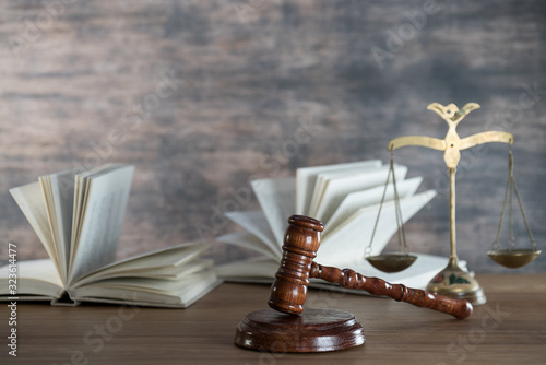 Law and Justice concept. Mallet of the judge, books, scales of justice. Gray stone background, reflections on the floor, place for typography. Courtroom theme.. Wooden rustic background photo