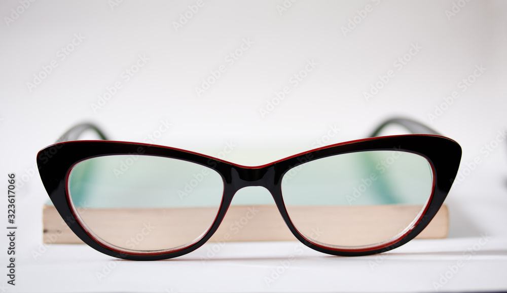 Modern black-rimmed glasses and a green book isolated on a white background. Modern black-rimmed glasses and a green book isolated on a white background.