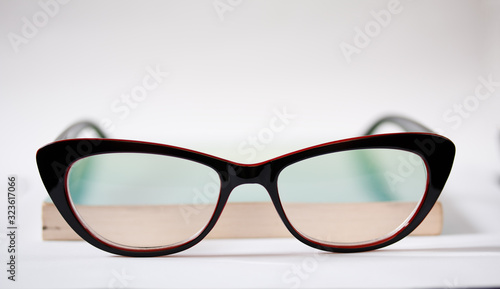 Modern black-rimmed glasses and a green book isolated on a white background.