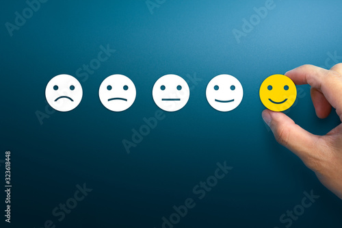 Customer service evaluation and satisfaction survey concepts. The client's hand picked the happy face smile face on blue background. copy space