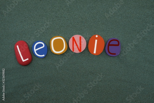 Leonie, female given name composed with colored stone letters over green sand photo