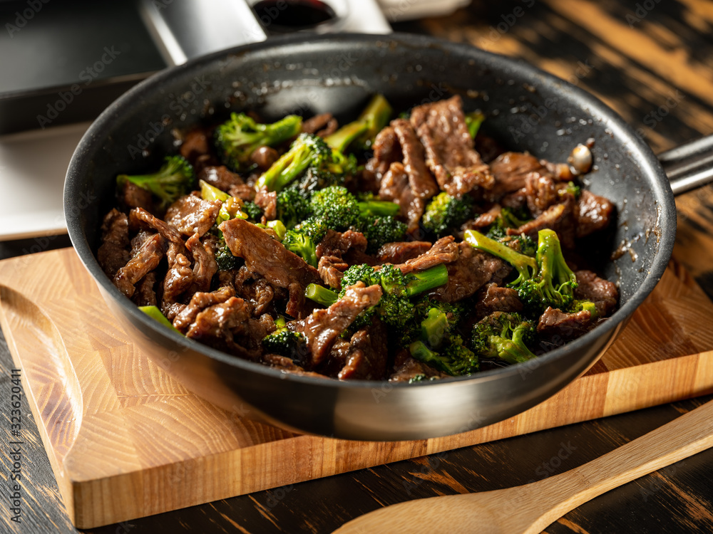 Beef meat and broccoli vegetable cooking in pan close up, selective focus. Traditional food recipe. Beef meat and broccoli vegetable cooking in pan close up, selective focus. Traditional food recipe.